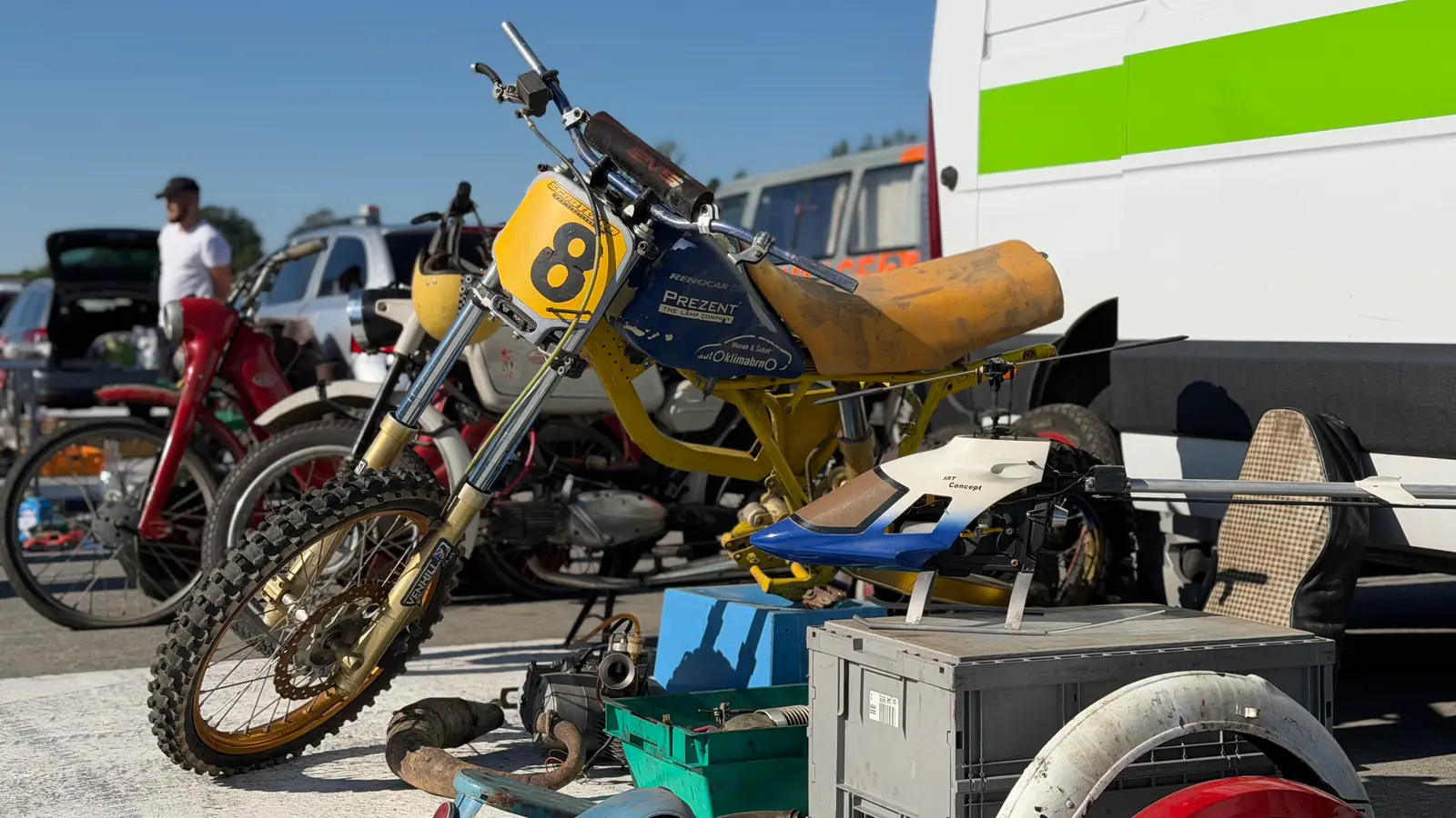 Žlutý motokrosový stroj s číslem 8 opřený vedle dodávky